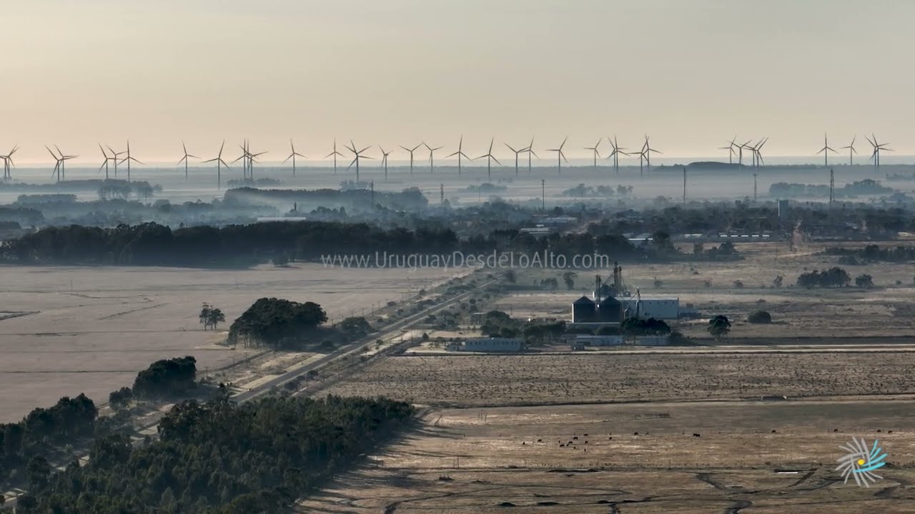 Video aéreo de molinos eólicos entre la bruma del amanecer próximos a Chuy
