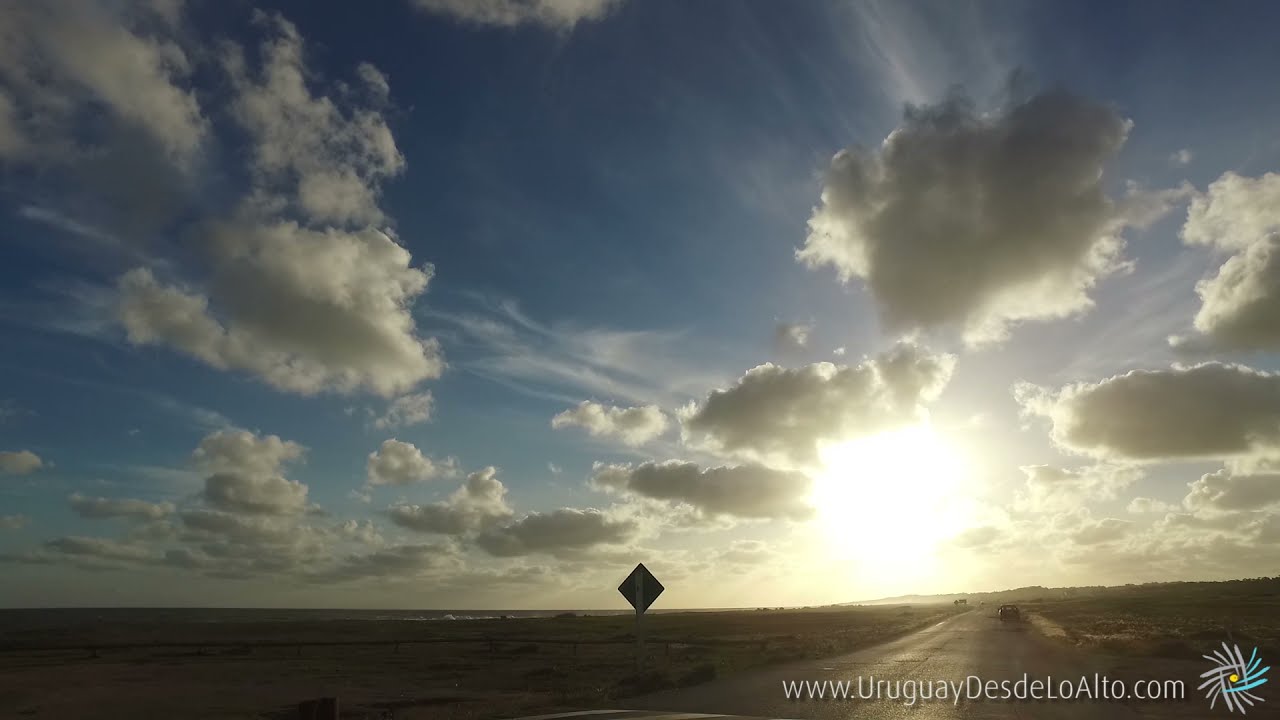 Video desde un automóvil por una ruta contra el sol y cielo con nubes